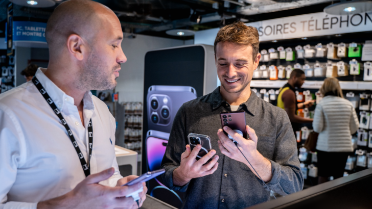 Hugo Clément discutant avec une personne devant un rayon des téléphones portables